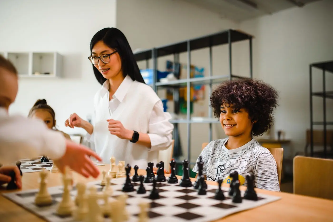 Enfants jouant aux échecs avec l’accompagnement d’une animatrice